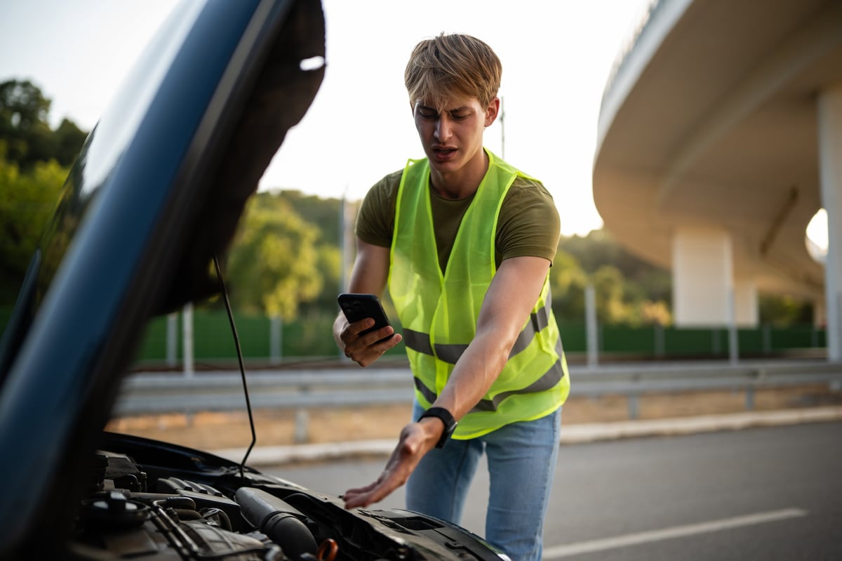 Driver in a safety vest calling for roadside assistance